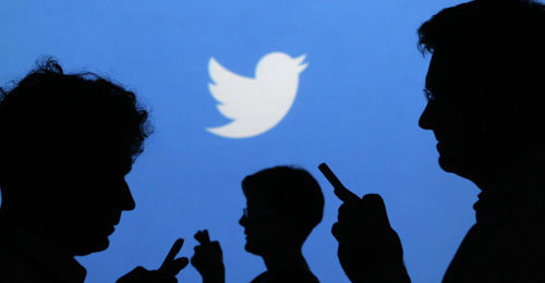 People holding mobile phones are silhouetted against a backdrop projected with the Twitter logo in this illustration picture taken in  Warsaw September 27, 2013. Twitter Inc, the eight-year-old online messaging service, gave potential investors their first glance at its financials on Thursday when it publicly filed its IPO documents, setting the stage for one of the most-anticipated debuts in over a year. Picture taken September 27.  REUTERS/Kacper Pempel (POLAND - Tags: BUSINESS TELECOMS LOGO)